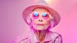 © Kasiwat - Stylish elderly woman enjoying retro fashion with sunglasses and hat, exuding vibrancy and confidence in a colorful background.