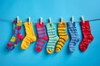 © Davy - Colorful socks hanging on a clothesline against an isolated blue background, national sock day