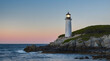 © ekalaila - Lighted Lighthouse on a Rocky Coast at Sunset
