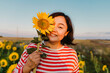 © VISTA by Westend61 - Smiling mature woman covering half face with sunflower in field