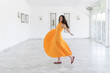 © VISTA by Westend61 - Happy woman in orange dress dancing in villa