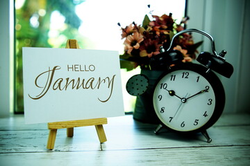 Wall Mural - Hello January text on paper card with easel and alarm clock in the window background