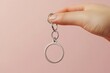 © Elegance Frames - A person showcasing a designer key ring with a solid color background, highlighting its elegant design and high-end materials.