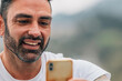 © carballo - portrait of attractive man with beard outdoors looking at mobile phone