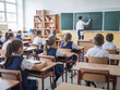 © StreamPixel - In the classroom, students in uniforms are seated at their desks, patiently awaiting the start of the lesson. The room is arranged with desks neatly aligned, a chalkboard at the front, and bookshelves