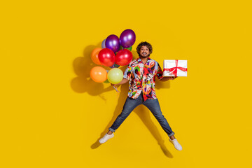 Poster - Full length photo of handsome young male air balloons jump present dressed stylish colorful garment isolated on yellow color background