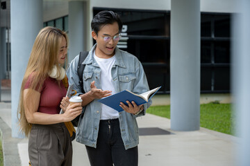 Two happy and cheerful young Asian college students are looking at a book