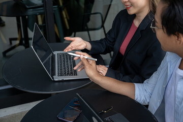 two businessmen discussing work using tablets and laptops in a modern coffee shop.