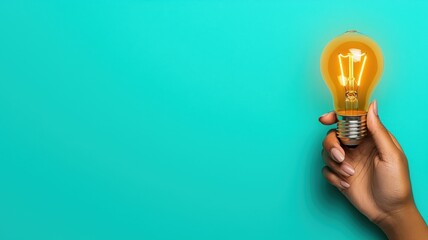 A hand holds a glowing light bulb against a bright turquoise background, symbolizing creativity and new ideas.