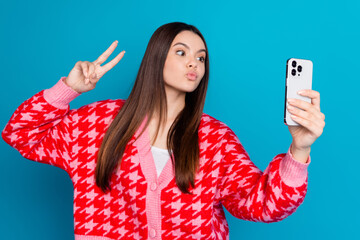 Wall Mural - Photo of pretty woman with straight hair dressed knit cardigan making selfie on smartphone show v-sign isolated on blue color background