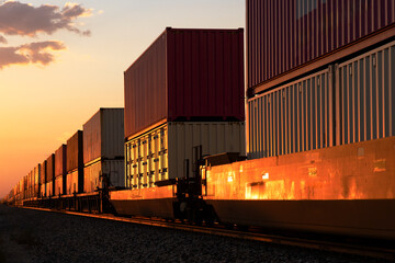 Sticker - The red glow of sunset on a passing container stack train