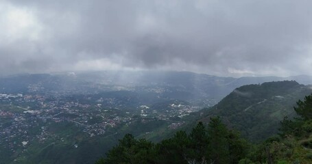 Wall Mural - A captivating cinematic image capturing a mountain range shrouded in foggy clouds moving along the mountains with rays of sunshine in Baguio