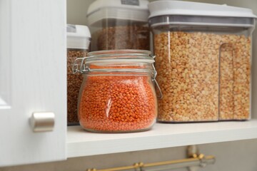 Wall Mural - Different types of cereals and legumes in containers in closet, closeup