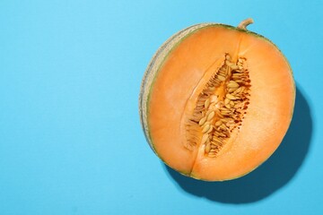 Canvas Print - Half of fresh Cantaloupe melon on light blue table, top view. Space for text