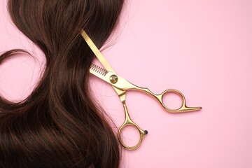 Canvas Print - Brown hair strand and professional scissors on pink background, top view