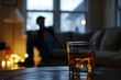 © juliars - Glass of whiskey with ice sitting on table with blurred caucasian man drinking alcohol in the background