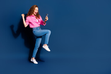 Wall Mural - Full body portrait of pretty young lady phone raise fist empty space wear shirt isolated on dark blue color background