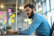 © Vooglo - A bearded man in a blue shirt is seated at an office desk