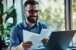 © Vooglo.com - A bearded man in a blue shirt, wearing glasses, is seated at a modern office desk
