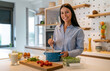 © NDABCREATIVITY - Portrait of a woman in the kitchen of her home for health diet or nutrition. Smile, food and cooking