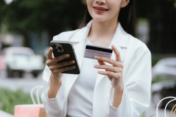 A stylish young Asian woman, cheerful and elegant, walks through a modern city mall, smiling with shopping bags. She enjoys luxury retail therapy, embodying a glamorous lifestyle.