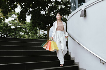 In vibrant Thailand, a happy young Asian woman enjoys a luxury shopping spree. Carrying stylish bags and vintage finds, she radiates joy, blending urban leisure with city life.