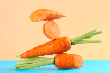 Whole and cut fresh carrots on color background