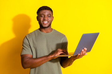 Wall Mural - Photo of cheerful nice man wear trendy khaki clothes hold use modern netbook isolated on yellow color background