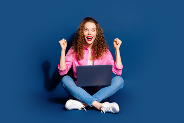 Poster - Full size photo of nice young woman sit floor raise fists laptop wear shirt isolated on dark blue color background