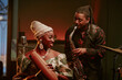 © AnnaStills - Cheerful young Black woman and man playing guiro and saxophone in jazz band on stage in local bar
