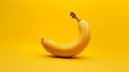 A single banana in the center of a bright yellow background