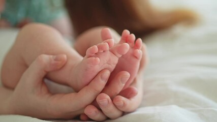happy family. tiny newborn infant male or female baby feet on mother hands. mother holding newborn c