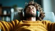 ©  lukaPixMedia - An individual lies back on a couch wearing headphones, completely relaxed and immersed in listening, with a sense of calm and contentment evident in their posture.