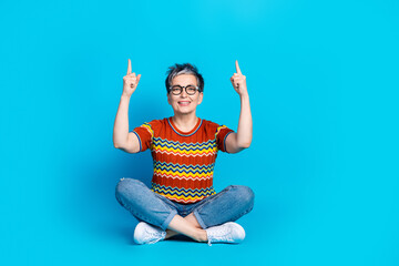 Sticker - Full body portrait of nice aged lady indicate fingers up empty space wear t-shirt isolated on blue color background