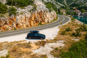  Car with a roof box stands on the side of a cliff and beautiful rocks in the background