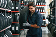 © standret - Carrying the tire. Man is in the tire fitting car service