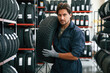 © standret - In gloves, professional worker with tire. Man is in the tire fitting car service