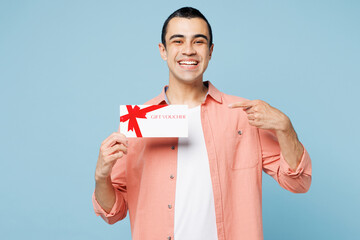 Poster - Young middle eastern man he wears pink shirt white t-shirt hold point finger on gift certificate coupon voucher card for store isolated on plain pastel light blue cyan background. Lifestyle concept.