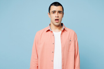 Poster - Young shocked upset displeased dissatisfied sad middle eastern man he wear pink shirt white t-shirt look camera isolated on plain pastel light blue cyan background studio portrait. Lifestyle concept.