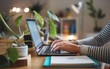 © Goashape-Studio - Home Office Productivity: Hands typing on laptop amidst houseplants, embodying the modern work-from-home lifestyle.