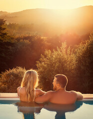 Young couple traveler relaxing and enjoying the sunset by a tropical resort pool while traveling for summer vacation
