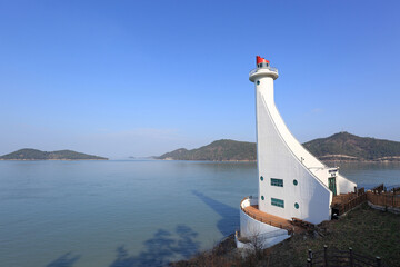 Wall Mural - Haenam-gun, Jindo-gun, Jeollanam-do, South Korea - December 15, 2021: Winter view of Mokpo Old Lighthouse against islands on the sea