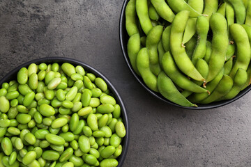 Raw green edamame soybeans and pods on grey table, top view