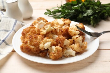 plate with tasty baked cauliflower on light wooden table, closeup