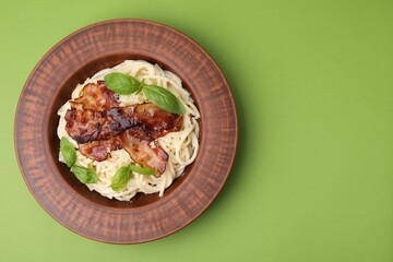 Wall Mural - Delicious pasta Carbonara with bacon and basil on green table, top view. Space for text