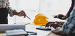 © Wasan - Brainstorming group of architects and engineers discuss building blueprint design paperwork and drawing construction project planning on wooden table in office. Construction project budget planning.