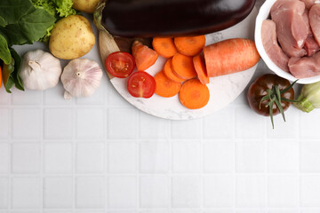 Wall Mural - Different vegetables and raw meat for stew on white tiled table, top view. Space for text