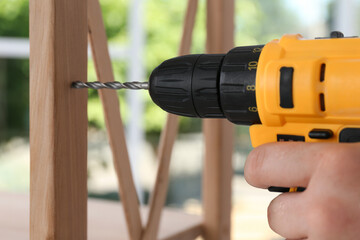 Canvas Print - Man with electric screwdriver assembling furniture indoors, closeup