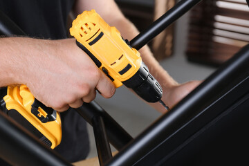 Wall Mural - Man with electric screwdriver assembling furniture in room, closeup