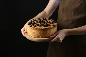 Wall Mural - Woman with delicious homemade blueberry pie on black background, closeup